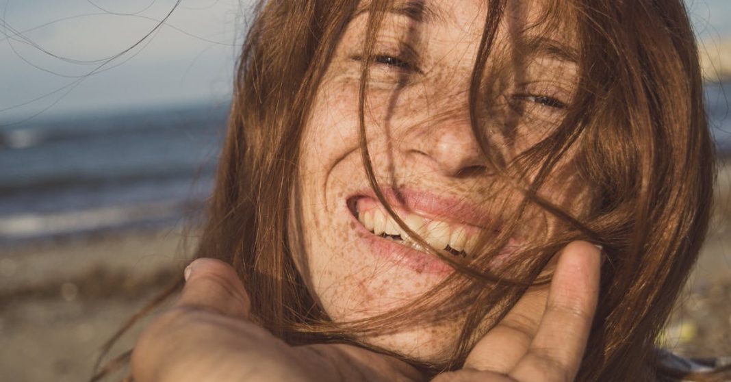 close-up-portrait-of-a-smiling-redhead-woman-on-a-beach-embracing-her-natural-beauty-8